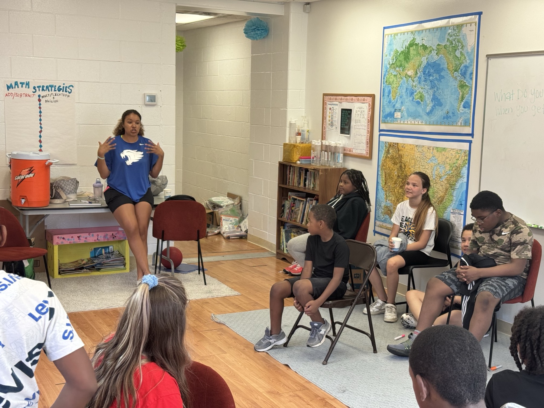 A Huddle mentor seated in a classroom teaching a small group of children